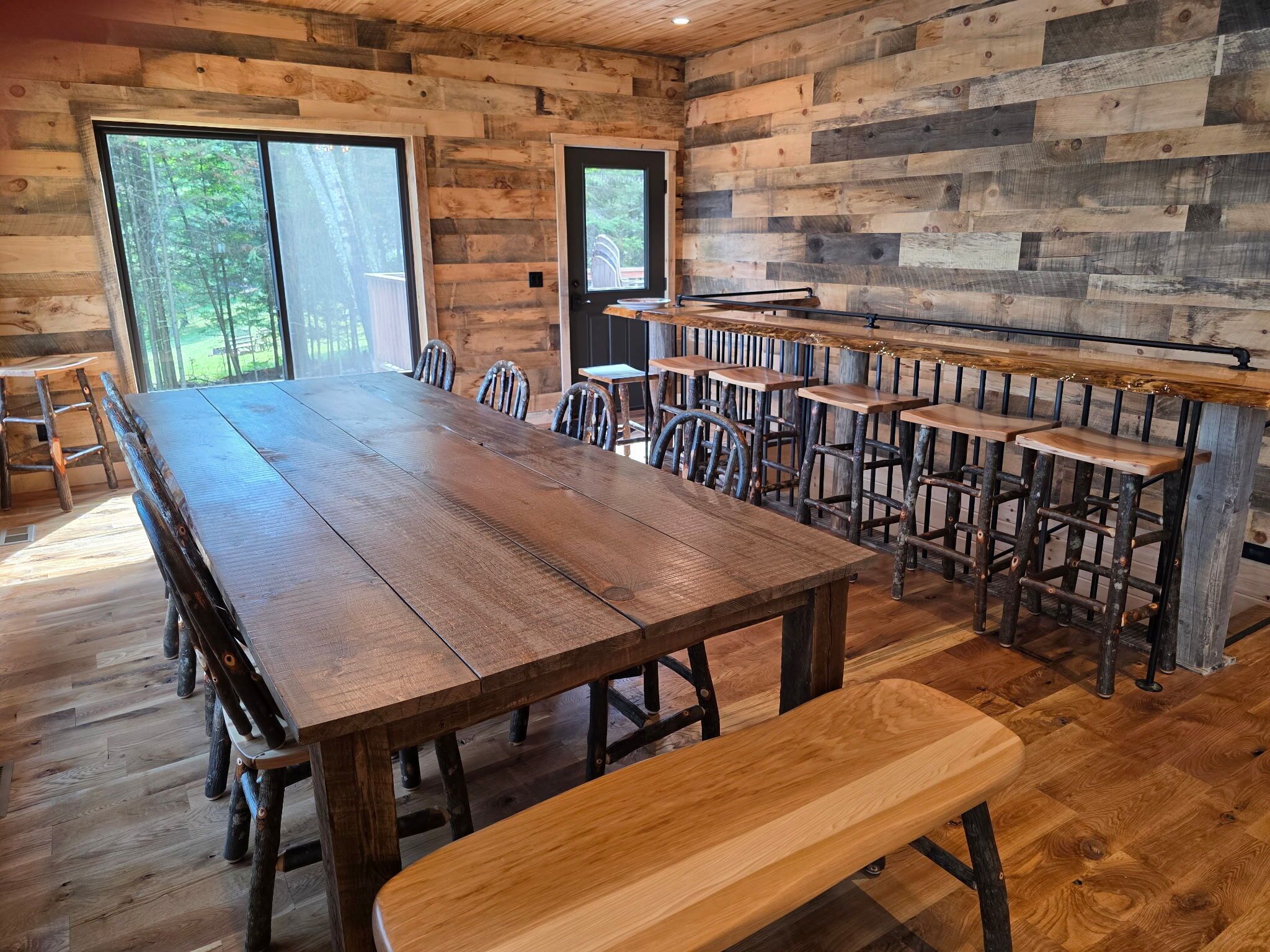 A rustic wooden interior with a long dining table, benches, and a bench at the table.