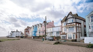 Une rangée de maisons colorées au bord de la mer, avec une plage de galets devant.