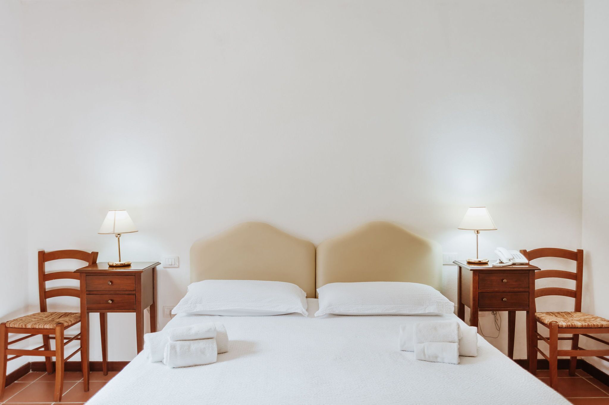 Ein Hotelzimmer mit einem Bett, zwei Nachttischen, zwei Sesseln und zwei Lampen.