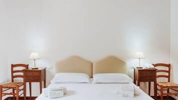 Ein Hotelzimmer mit einem Bett, zwei Nachttischen, zwei Sesseln und zwei Lampen.