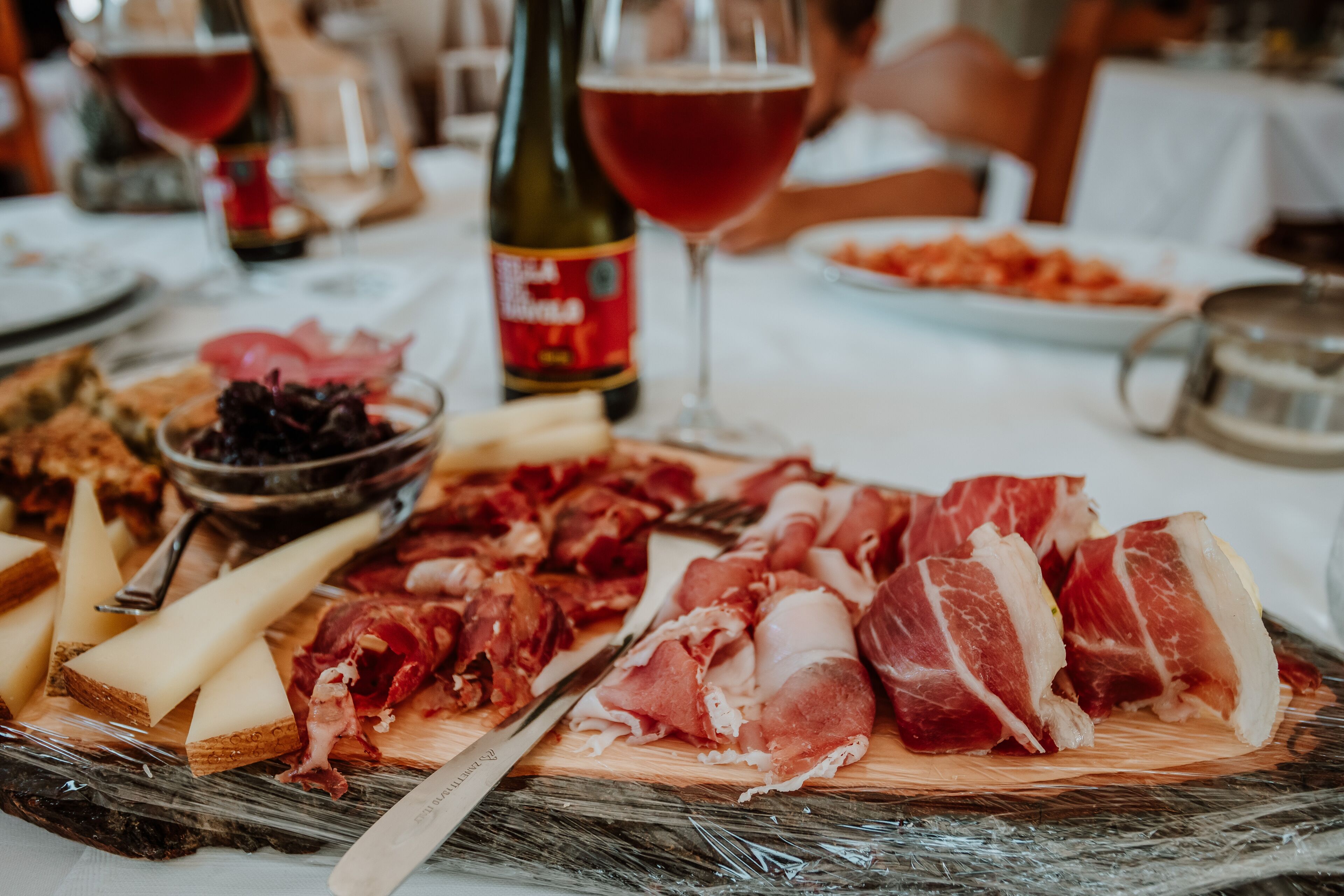 A charcuterie board with various meats, cheeses, and a bottle of wine on a table.