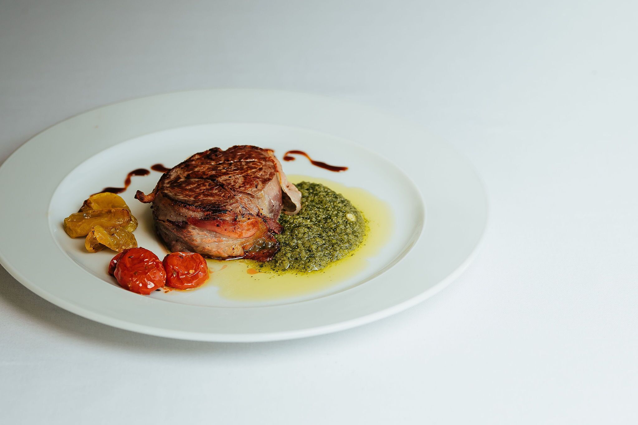 Ein Teller mit Fleisch, Gemüse und einer grünen Soße.