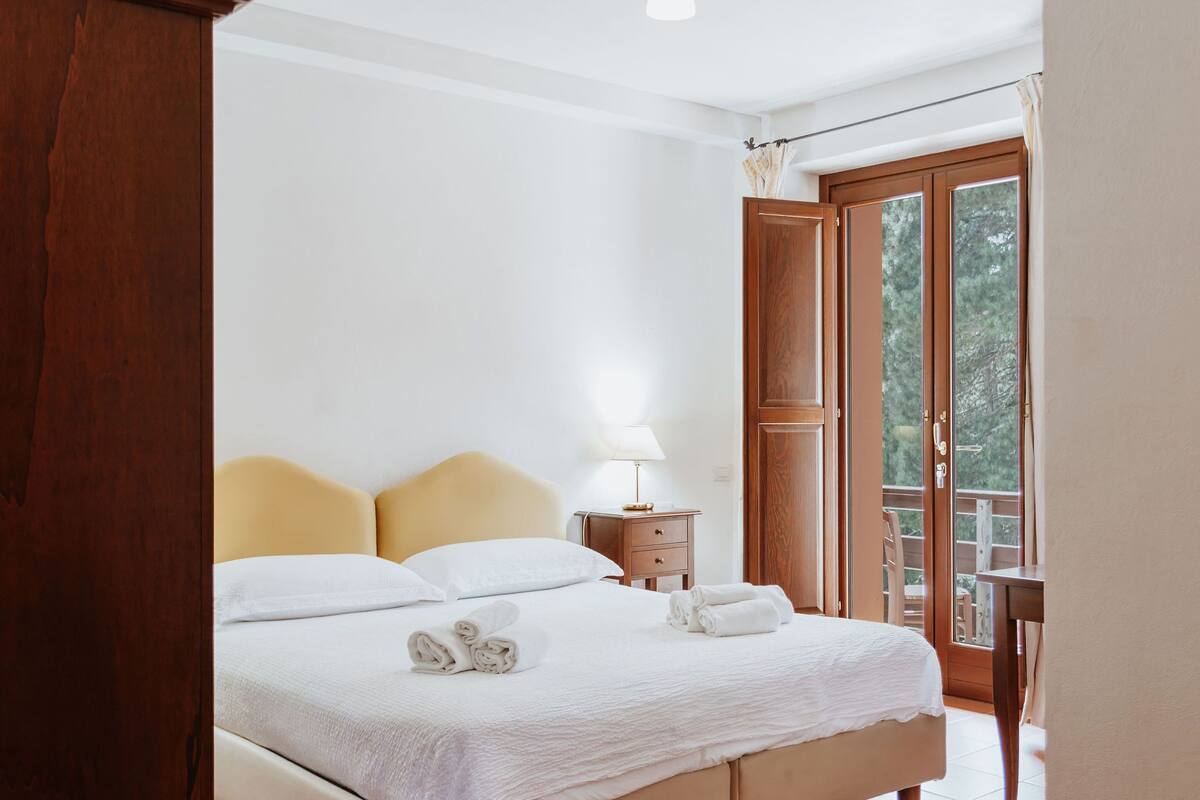 Une chambre à coucher avec un lit, une table de chevet et une vue sur l’extérieur par une porte.