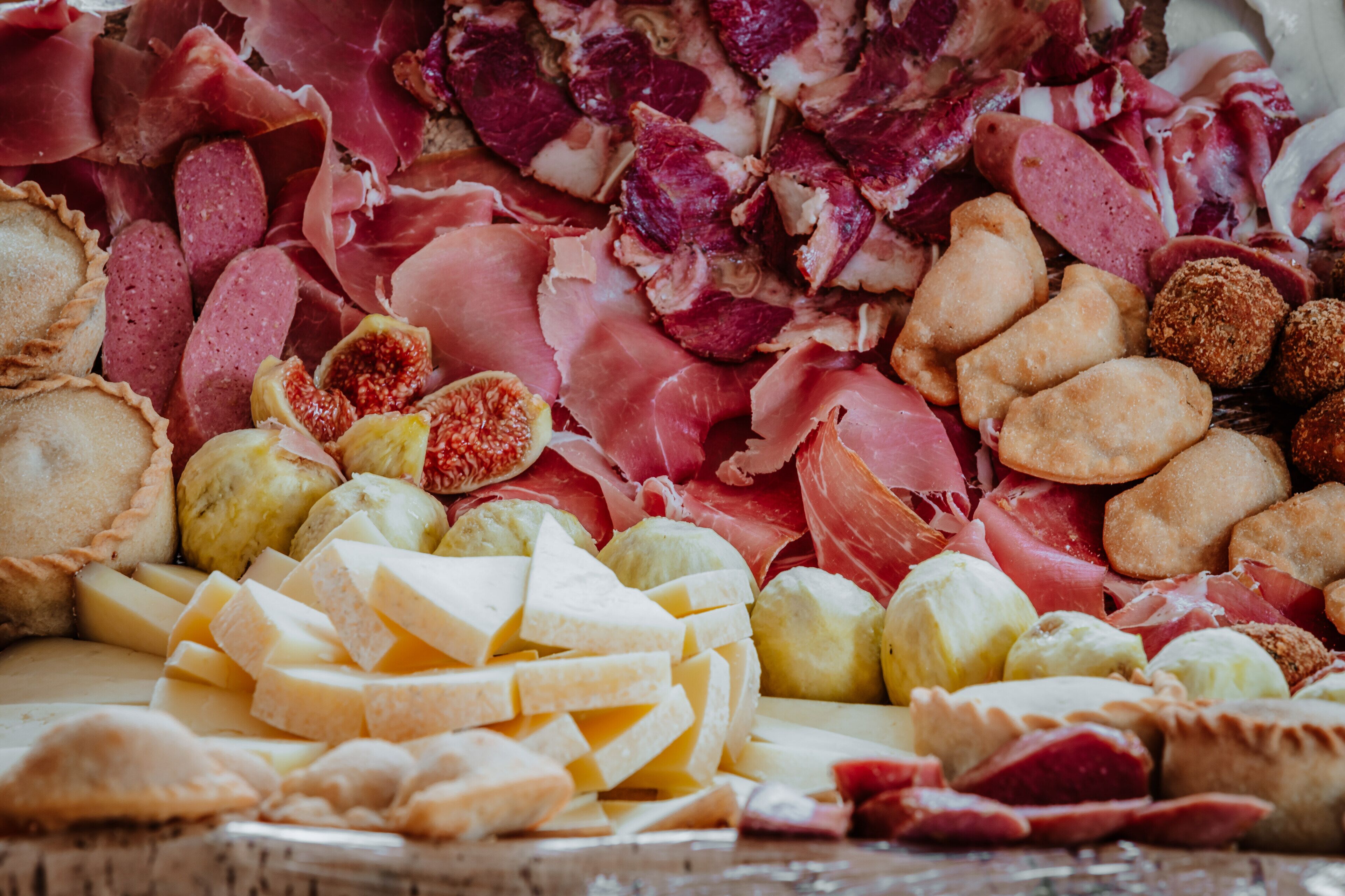 A charcuterie board with various meats, cheeses, and fruits.