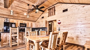 Un interior de madera con una mesa de comedor y sillas, una zona de cocina y un ventilador de techo.