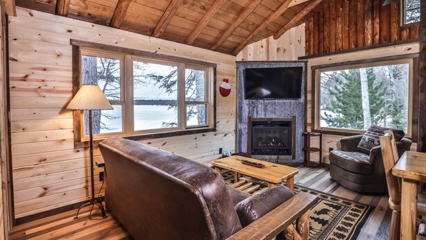 Interior acogedor de una cabaña con un sofá de cuero, una mesa de madera y una chimenea.