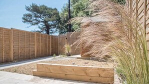 A wooden deck with a raised planter and a wooden fence. - 3 Oaks Court, Thorpeness (Leiston)