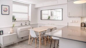 A modern kitchen with a central island, white cabinetry, and a large window with blinds.