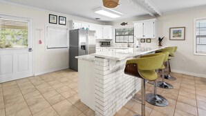 A kitchen with white cabinetry, a central island, and bar stools.