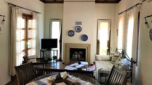 A cozy living room with a fireplace, a dining table, and a television. - Olive Grove Villa, private pool & whirl pool, total privacy (Marmaris)