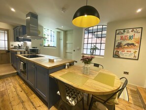 Una cucina moderna con isola centrale, pavimento in legno e zona pranzo con tavolo e sedie.