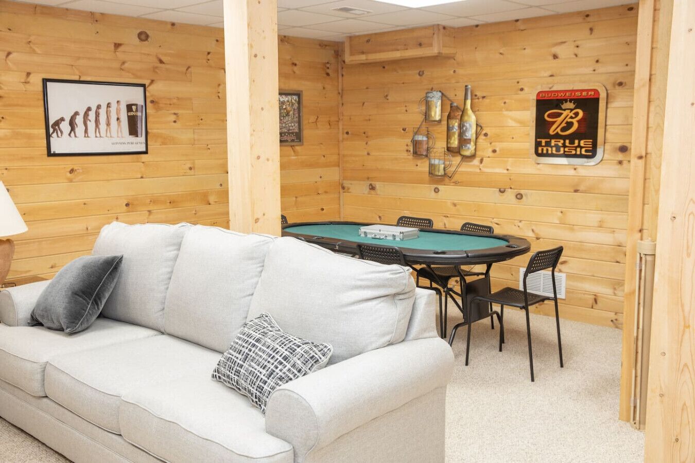 A cozy room with a wooden interior, a pool table, and a couch with pillows.
