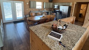 A spacious kitchen with granite countertops, wooden cabinetry, and a dining area with a large island.