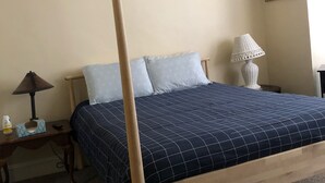 A bedroom with a four-poster bed, a nightstand with a lamp, and a bedside table with a tissue box.