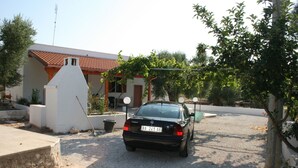 Ein schwarzes Auto vor einem Haus mit einem Ziegeldach und einem weißen Schornstein.