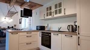 Ett modernt kök med vita skåp, en inbyggd ugn, en mikrovågsugn och en kaffebryggare.