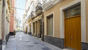 A narrow cobblestone street lined with buildings, featuring a wooden door with a number '15' and a bicycle parked nearby. - COLON15 Family Home by Cadiz4Rentals (Cádiz)