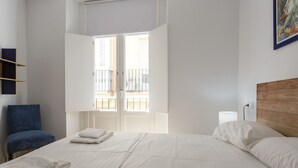 A bedroom with a bed, a chair, a window, and a painting on the wall. - COLON15 Family Home by Cadiz4Rentals (Cádiz)