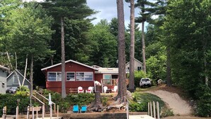 Un chalet au bord du lac, doté d’un quai, d’un espace salon extérieur et d’un véhicule garé à proximité.