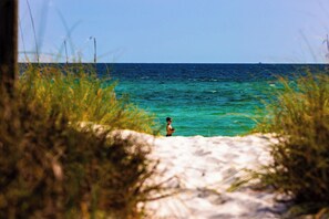 A person standing on a sandy beach with clear turquoise water in the background. - Pet Friendly Two Bedroom Condo with pool outside your back door. Seahorse (Panama City Beach)