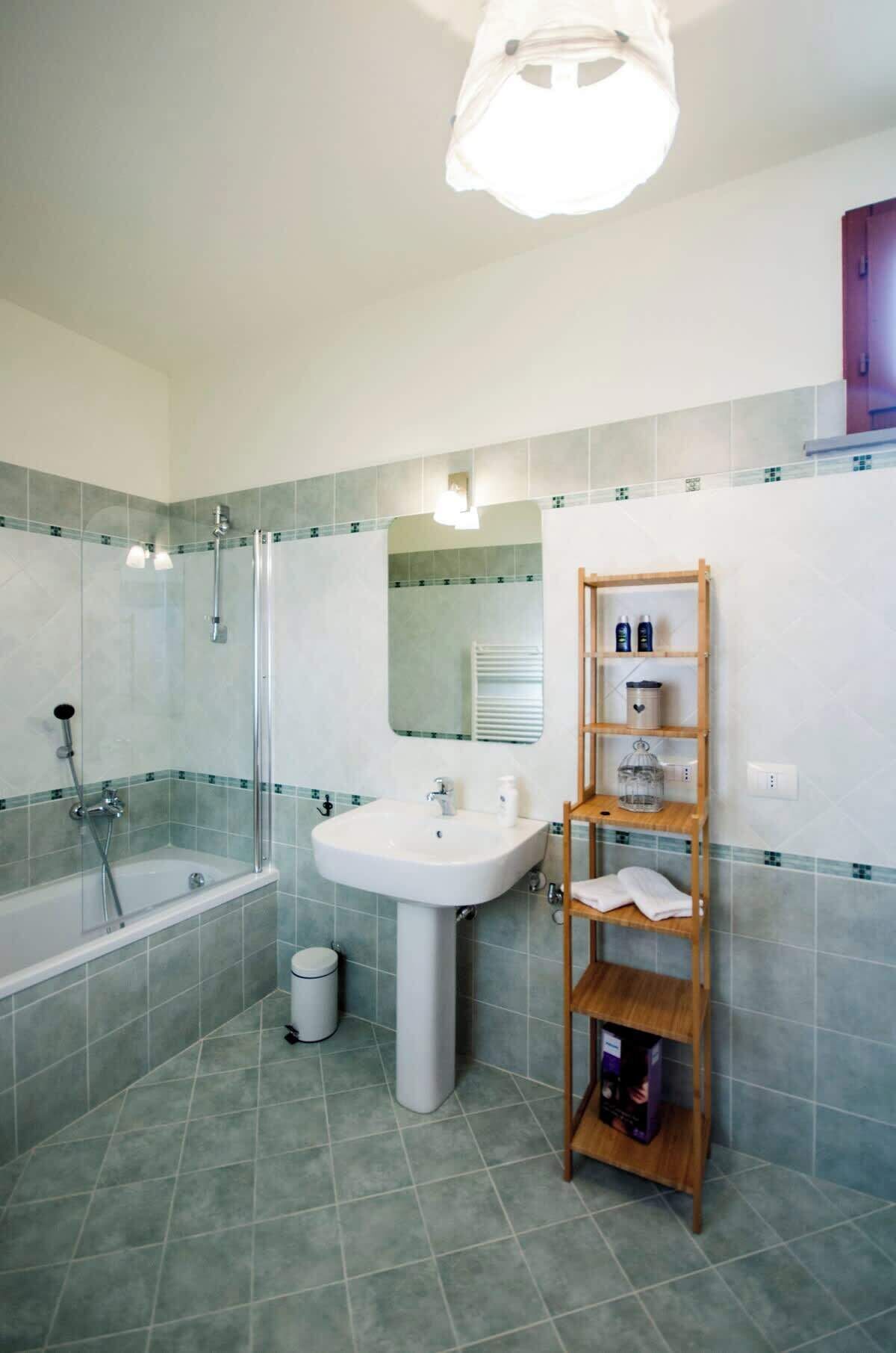 A bathroom with a bathtub, a sink, and a wooden shelf with toiletries.