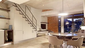 Eine moderne Küche mit Essbereich, inklusive Treppe, Backsteinwand und Blick auf die Stadtlandschaft.