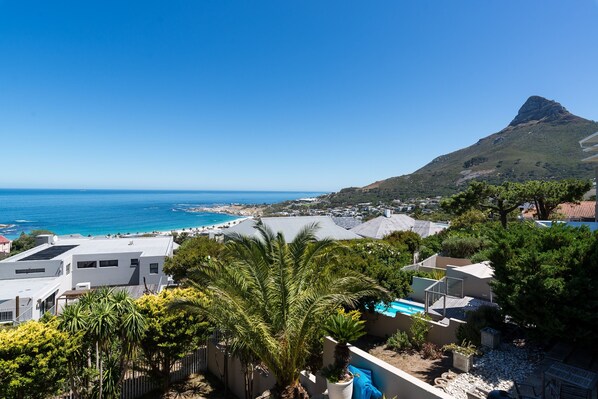 A coastal view with a mountain, a swimming pool, and residential buildings.