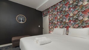 Ett hotellrum med en stor säng, en rund väggdekoration och en blommig tapet.