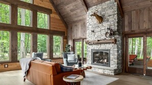 A spacious living room with a stone fireplace, large windows, and a cozy seating area.
