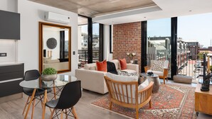 Un salon moderne doté d’une grande fenêtre, d’un mur en briques et d’un balcon.