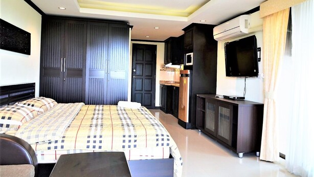 Un dormitorio moderno con una cama grande, armario, unidad de aire acondicionado integrada y televisor.