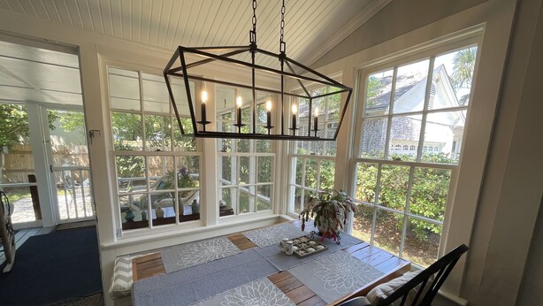 A dining area with a wooden table, white tablecloth, and a hanging light fixture.
