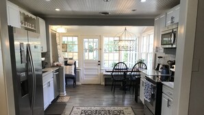 A modern kitchen with a refrigerator, microwave, and stove. There is a dining area with chairs and a table.