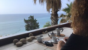Une table avec vue sur la mer, une théière, des tasses et une assiette de biscuits.