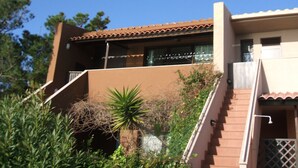 Un immeuble de deux étages, à la façade brune, doté d’un balcon et d’un escalier menant à l’étage supérieur.