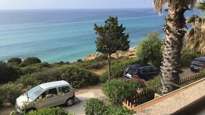 Une vue sur la côte, avec une voiture garée et un fourgon blanc sur une allée, le tout entouré de verdure et d’un mur de pierres.