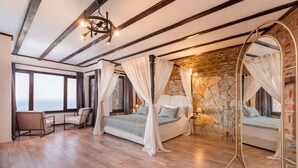 Un dormitorio con una cama grande, una zona de estar con una silla, una mesita pequeña y un espejo grande.
