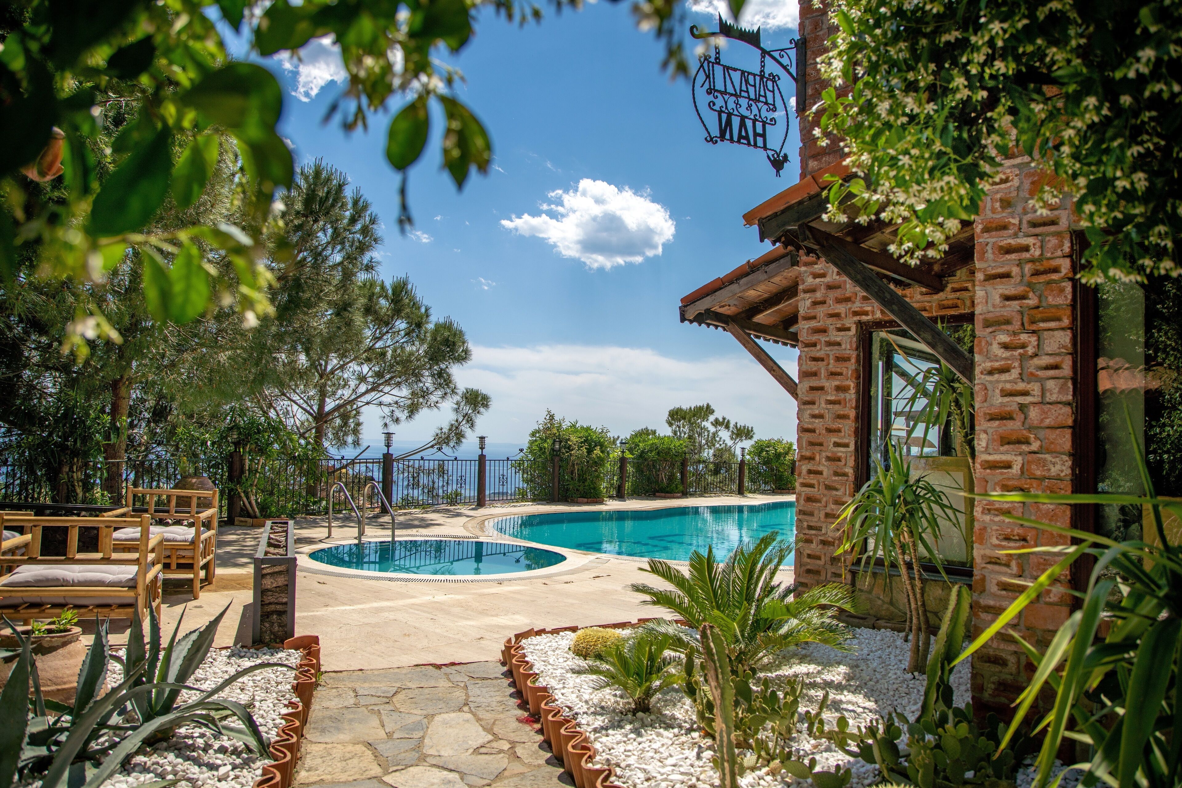A pool area with two swimming pools, surrounded by potted plants and a wooden deck.