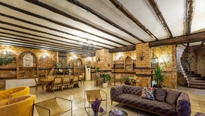 Un amplio salón con vigas de madera a la vista, una chimenea y una escalera que sube a un nivel superior.