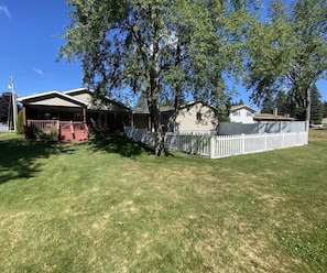En bostadsfastighet med ett hus, en inglasad veranda och en inhägnad trädgård.