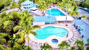 A resort with two swimming pools, lounge areas, and palm trees. - SPRAWLING PRIVATE BEACHFRONT - Sleeps 10, perfect for a family, 2 golf carts (Upper Captiva)