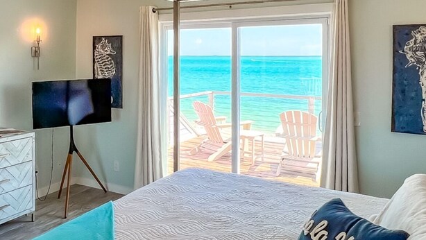 A bedroom with a large bed, a desk, and a view of the ocean. - SPRAWLING PRIVATE BEACHFRONT - Sleeps 10, perfect for a family, 2 golf carts (Upper Captiva)