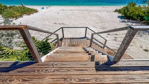 A wooden staircase leading to a beach with clear blue water and a sandy shore. - SPRAWLING PRIVATE BEACHFRONT - Sleeps 10, perfect for a family, 2 golf carts (Upper Captiva)