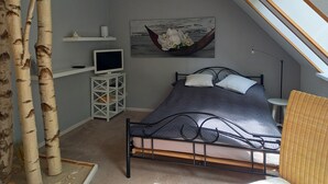 Una camera da letto con un letto, una TV su un mobile, un quadro e una finestra.