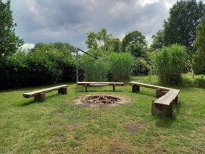 An outdoor seating area with benches and a fire pit surrounded by greenery.