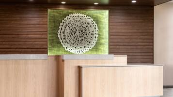 Een receptiebalie met een houten afwerking, een groot rond kunstwerk aan de muur en een modern plafondontwerp.