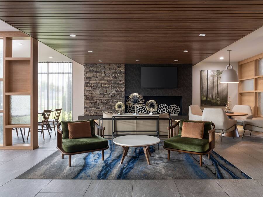 A modern living room with a fireplace, a flat-screen TV, and a round coffee table.