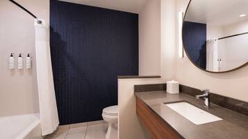 A modern bathroom with a bathtub, toilet, vanity with a sink, and a large mirror.
