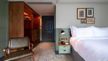 A hotel room with a bed, a chair, a wardrobe, a nightstand, and a door.