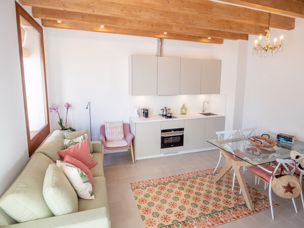 A modern kitchen with white cabinets, a built-in oven, and a glass dining table with chairs.